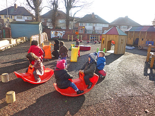 Lots of children playing with play equipment in the nursery playground